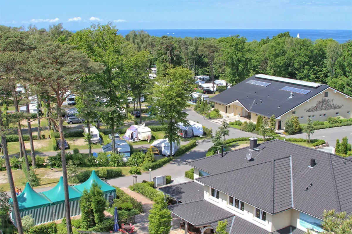 Camping.info No. 1 in Germany: Kühlungsborn campsite. You can see an aerial view of a campsite in the countryside, with the sea in the background.