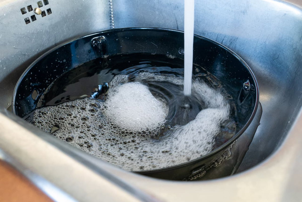 Cleaning the CADAC grill grease tray: soaking with hot water and dish soap