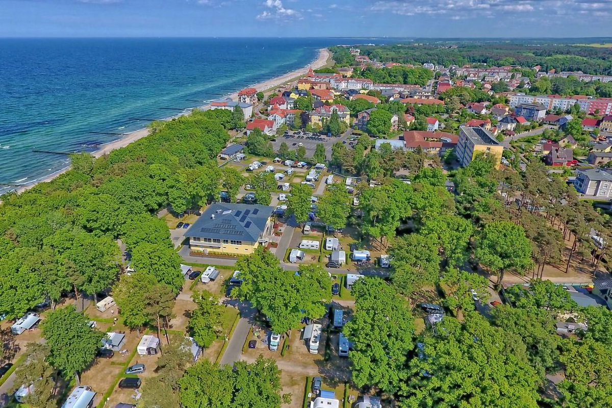 Camping.info No. 1 in Germany: Kühlungsborn campsite. You can see an aerial view of a campsite in the countryside, with the sea in the background.