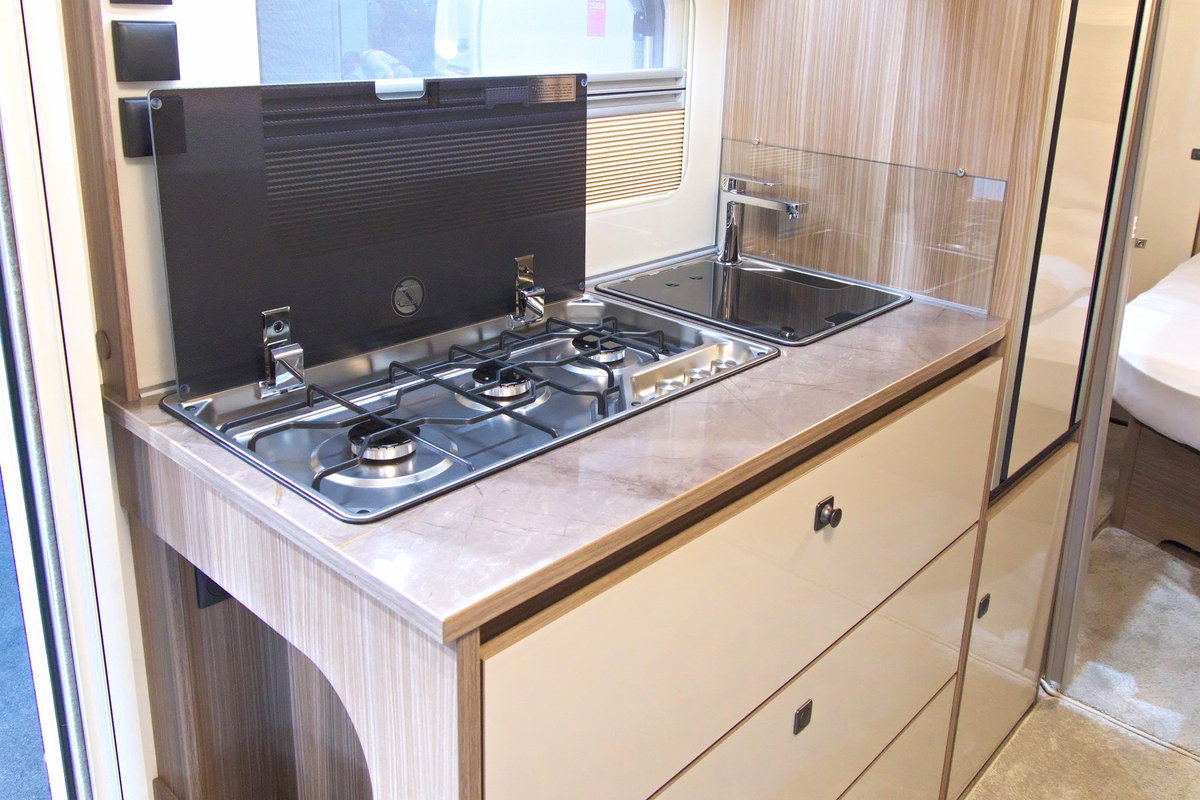 Fendt Tendenza 560 SFDW at Caravan Salon 2026: Kitchen unit with 3-burner stove, sink, fridge and storage space.